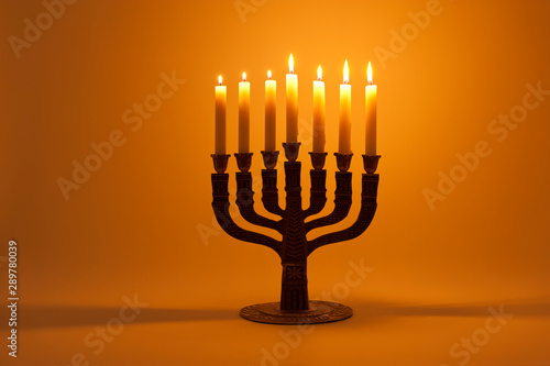 Menorah with 7 lighted candles isolated on golden background. Horizontal shot.