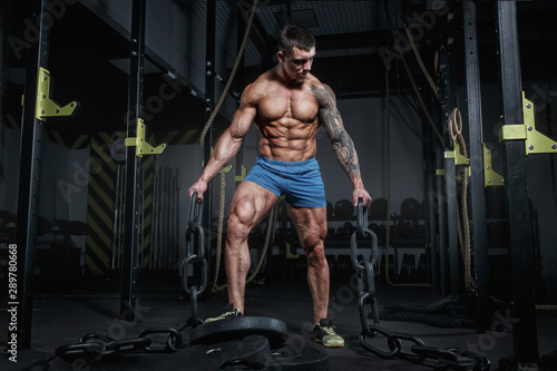 Athletic pumped man bodybuilder with chain in hall of crossfit