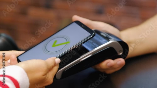 Hand of young woman pays for purchases using the contactless payment nfs system