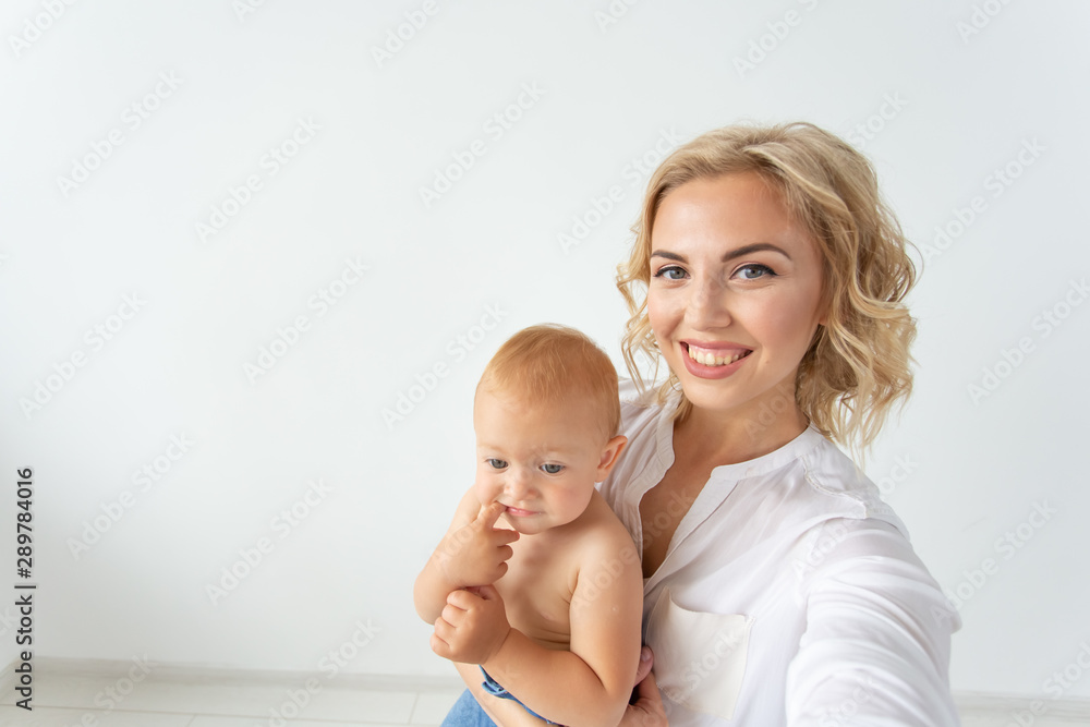 Cute little baby girl and her mother taking selfie in a living room. Cute little baby girl and her mother taking selfie in a living room.
