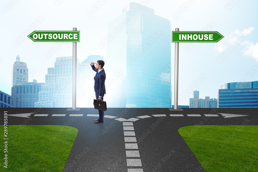 Businessman at crossroads deciding between outsourcing and inhou Businessman at crossroads deciding between outsourcing and inhou