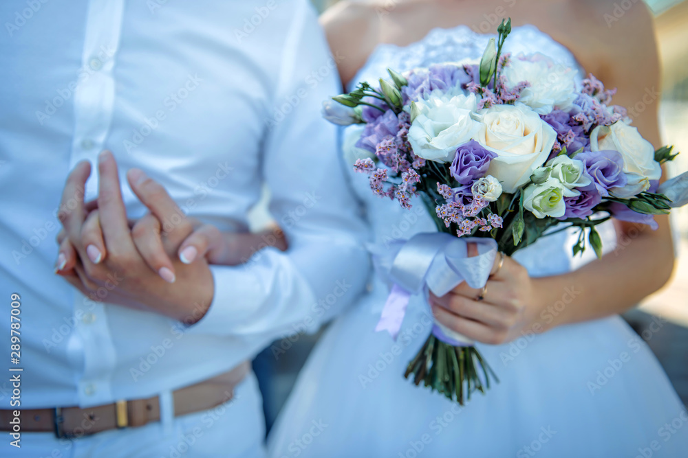 New marriage couple. Bride with wedding bouquet holds the groom's arm. Stylish newlyweds. Wedding concept. New marriage couple. Bride with wedding bouquet holds the groom's arm. Stylish newlyweds. Wedding concept.