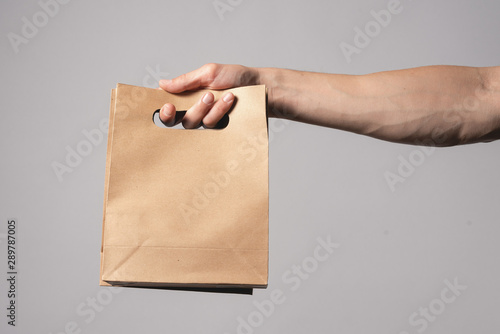 A shopping bag in a male hand isolated on gray background.