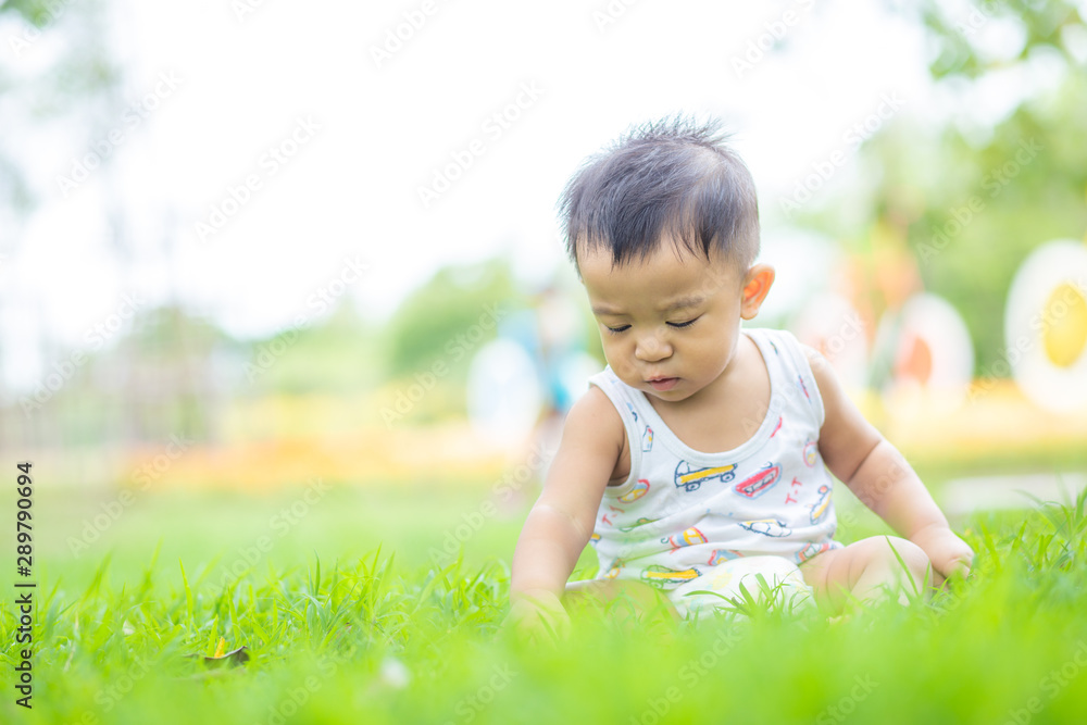 Adorable little boy sitting in green park field Adorable little boy sitting in green park field