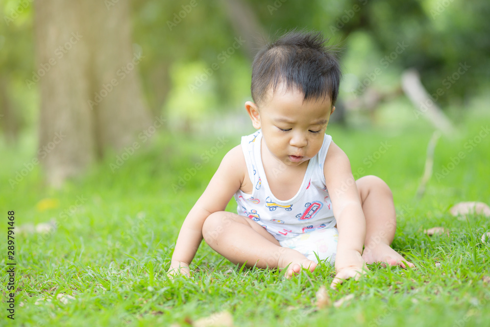 Adorable little boy sitting in green park field Adorable little boy sitting in green park field