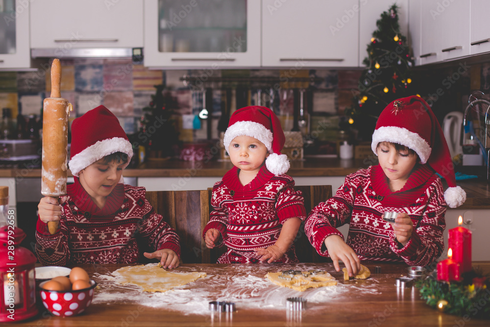 Sweet toddler child and his older brother, boys, helping mommy preparing Christmas cookies at home . Sweet toddler child and his older brother, boys, helping mommy preparing Christmas cookies at home .