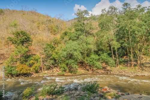 view of river flowing around with many arch rocks and green forest with the hills and blue sky background, Ob Luang National Park, Chiang Mai, northern of Thailand.