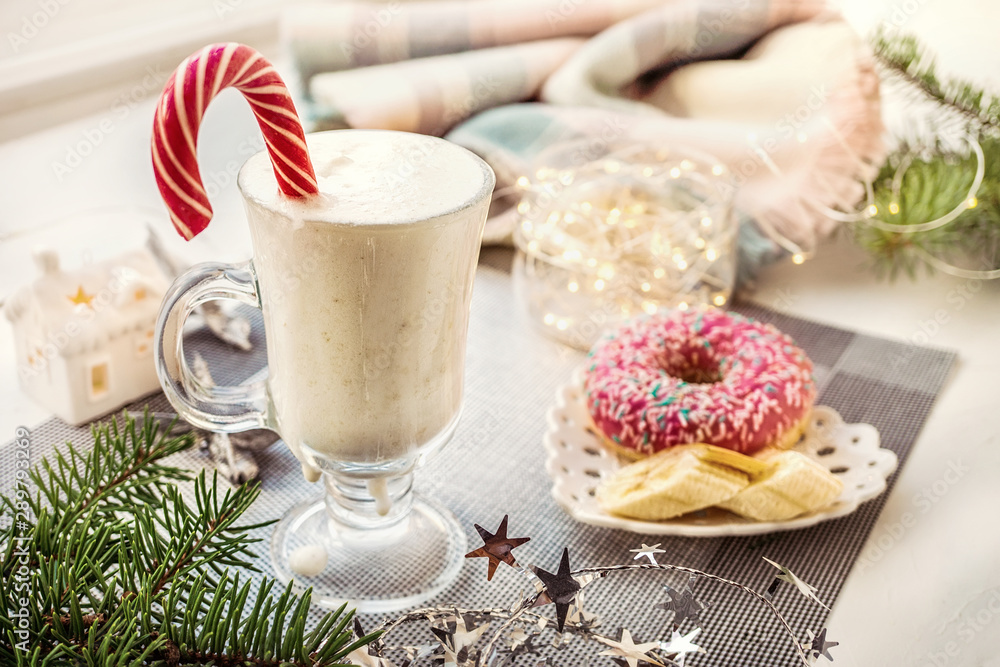 Irish traditional winter cream cocktail eggnog in a glass mug with milk, rum and cinnamon, banana covered with whipped cream, Christmas decorations. Natural smoothies Irish traditional winter cream cocktail eggnog in a glass mug with milk, rum and cinnamon, banana covered with whipped cream, Christmas decorations. Natural smoothies