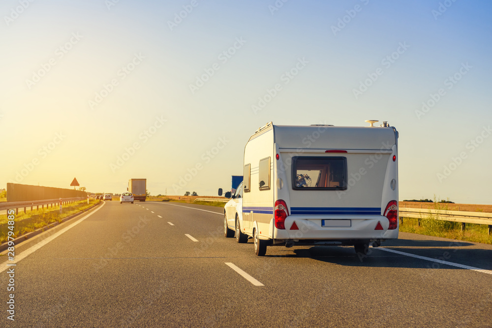 Car with recreational vehicle motor home trailer on highway. Family vacation trip concept.