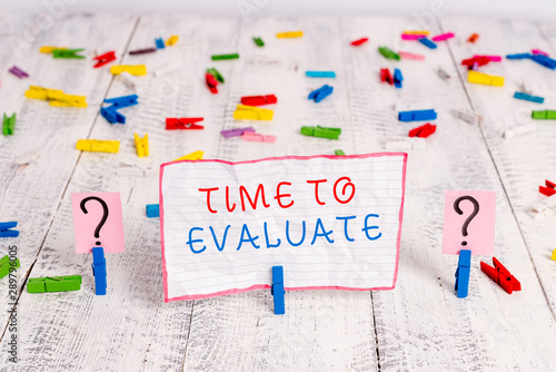 Handwriting text writing Time To Evaluate. Conceptual photo judge something with respect to its worth or significance Scribbled and crumbling sheet with paper clips placed on the wooden table