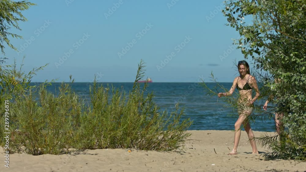 Girls in bikinis walking along sandy beach towards camera in slow motion Girls in bikinis walking along sandy beach towards camera in slow motion