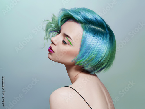 Portrait of a woman with bright colored flying hair, all shades of blue purple. Hair coloring, beautiful lips and makeup. Hair fluttering in the wind. Sexy girl with short  hair. Professional coloring