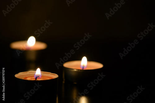 Three burning candles close up in the darkness. Mystery background