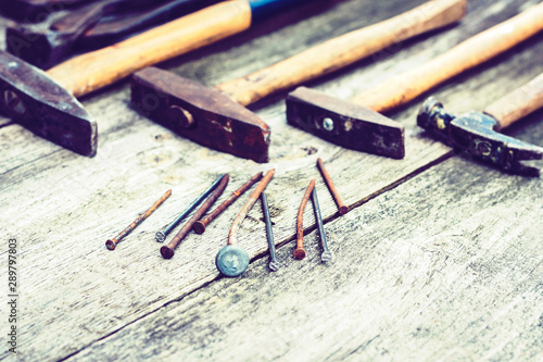 Set of vintage hand construction tools hammers with nails on a wooden background, retro concept .