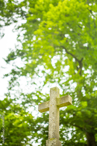 Jesus Christ cross in concrete with trees as background.