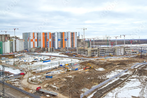 Construction site, construction of a large residential complex on the background of new houses and forests © vizland
