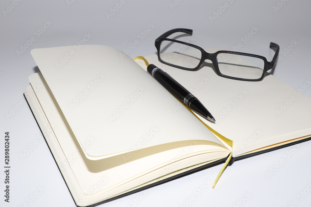 glasses, notebook and pen on the table in the office glasses, notebook and pen on the table in the office
