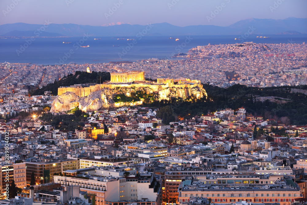 Cityscape of Athens with illuminated Acropolis hill, Pathenon and sea at night, Greece