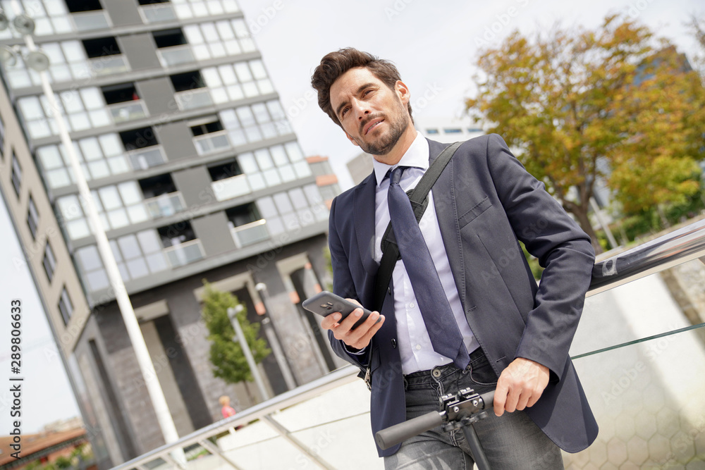 Businessman on the street using smartphone and electric scooter Businessman on the street using smartphone and electric scooter