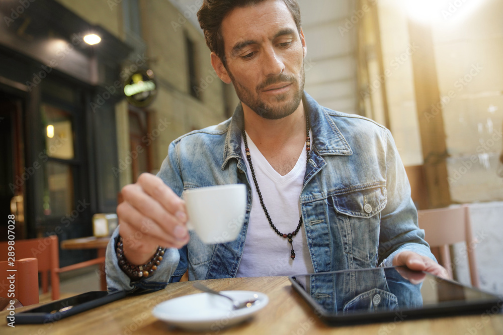 Fototapeta premium Trendy guy connected on tablet at coffee shop