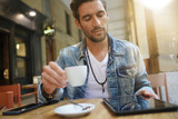 Trendy guy connected on tablet at coffee shop