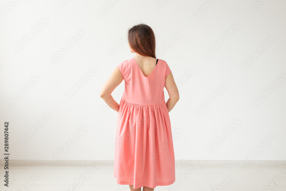Beautiful young cheerful woman in a bright pink dress posing on the background of a white wall with copy space. The concept of stylish feminine images. Beautiful young cheerful woman in a bright pink dress posing on the background of a white wall with copy space. The concept of stylish feminine images.