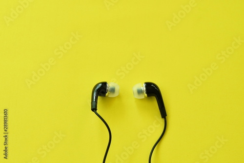 black earphone for conecting with mobile phon arranging on yellow foam board background photo