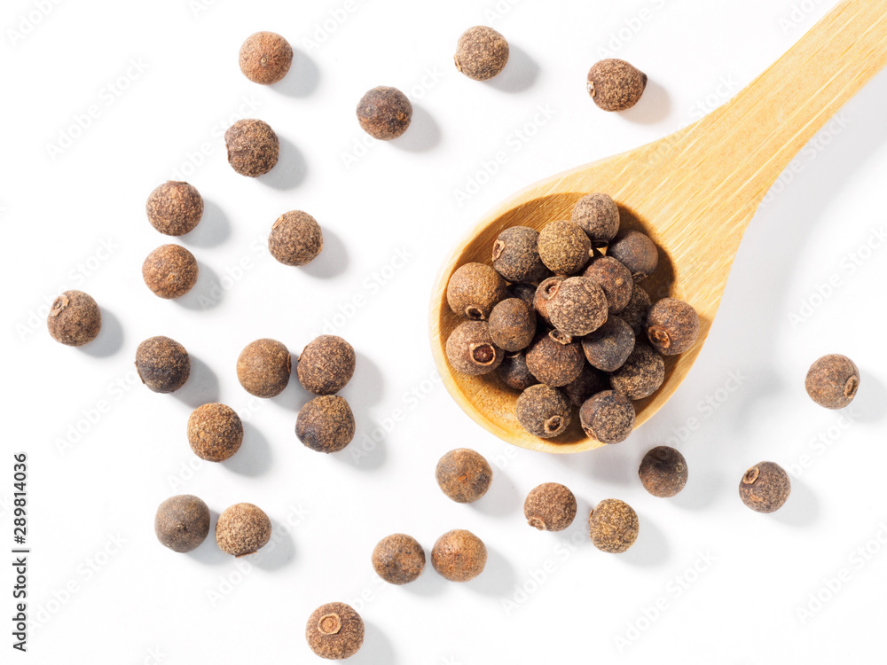 Allspice (Jamaica pepper) in the wooden spoon diagonally on white background Allspice (Jamaica pepper) in the wooden spoon diagonally on white background