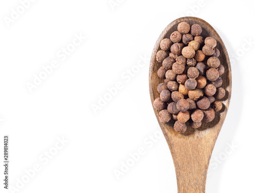 Allspice (Jamaica pepper) in the wooden spoon vertically on white background