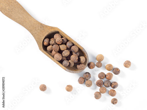 Allspice (Jamaica pepper) in wooden scoop diagonally on white background