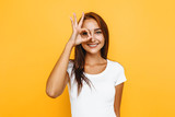 Young cheerful girl showing zero gesture on a yellow background
