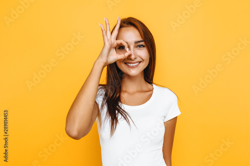 Young cheerful girl showing zero gesture on a yellow background photo