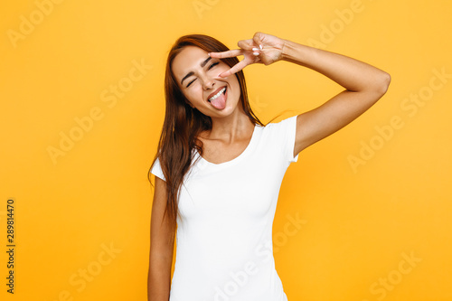 Beautiful girl shows double v-sign on yellow background background
