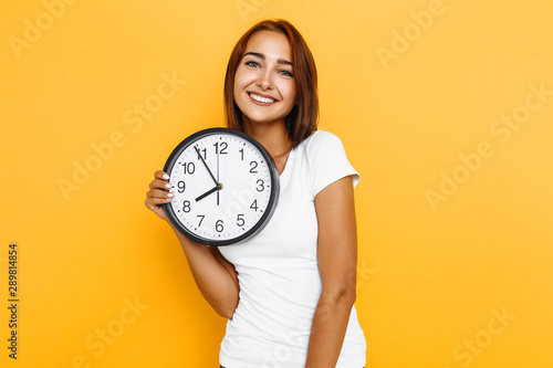 Young attractive woman with a watch on a yellow background