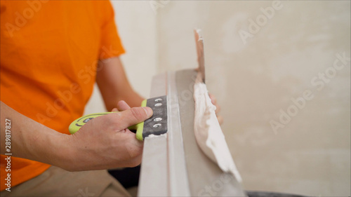A worker puts a mortar on a spatula. Plastering walls. White mortar on a spatula