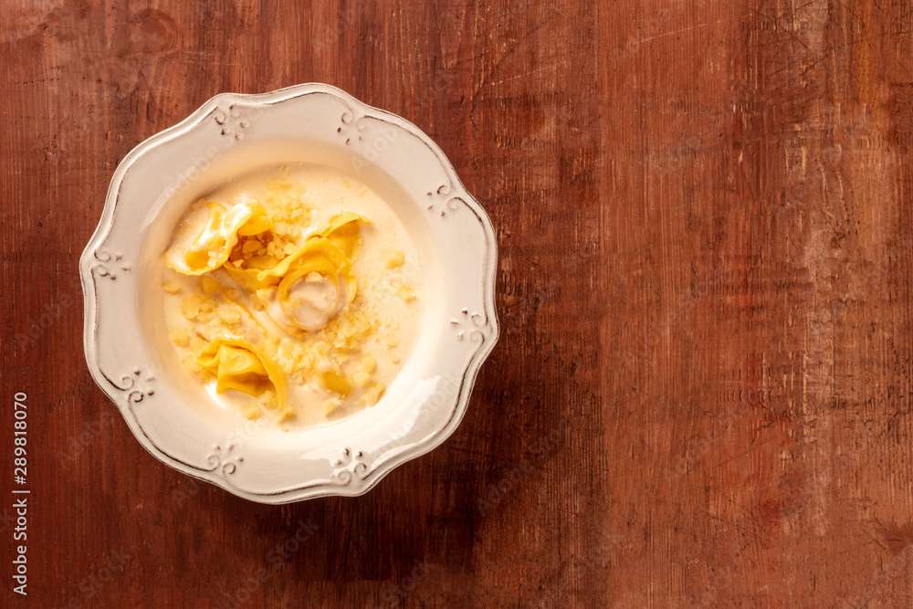 Italian tortellini in a cream sauce with grated Parmesan cheese, shot from above on a dark rustic wooden background with copyspace Italian tortellini in a cream sauce with grated Parmesan cheese, shot from above on a dark rustic wooden background with copyspace