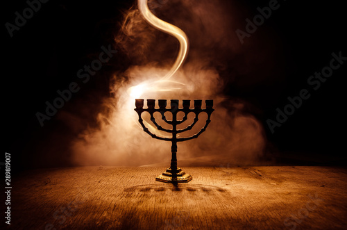 Low key image of jewish holiday Hanukkah background with menorah on dark toned foggy background photo