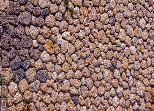 Abstract background – old stone wall exterior, rough brown rock surface texture. 