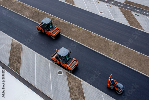 Asphalt roller compactor on site, compacting new asphalt pavement in urban modern city