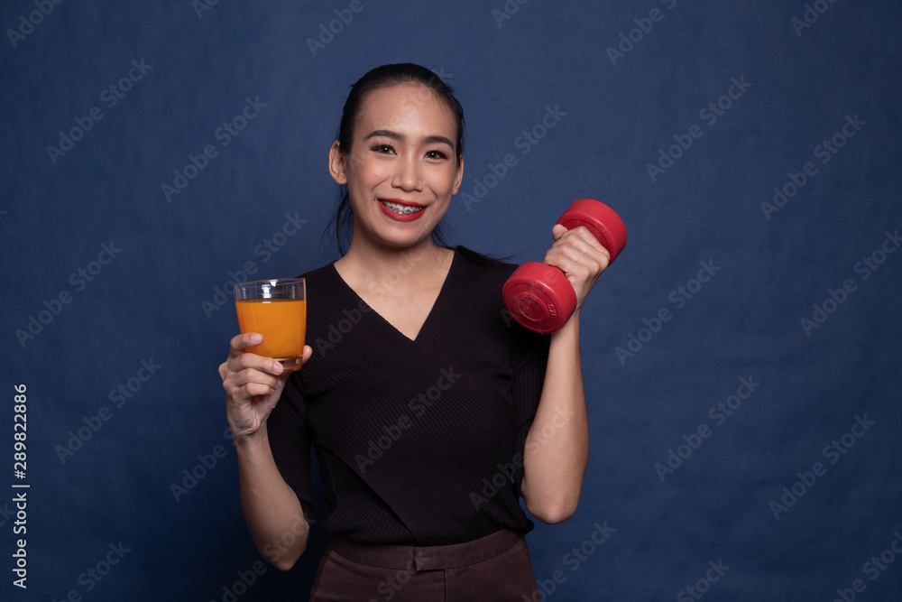 Young Asian woman with dumbbell drink orange juice. Young Asian woman with dumbbell drink orange juice.