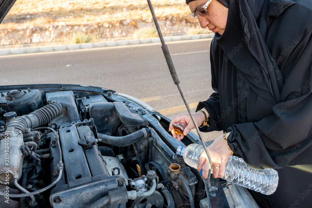 Muslim arabic woman filling her car with water
