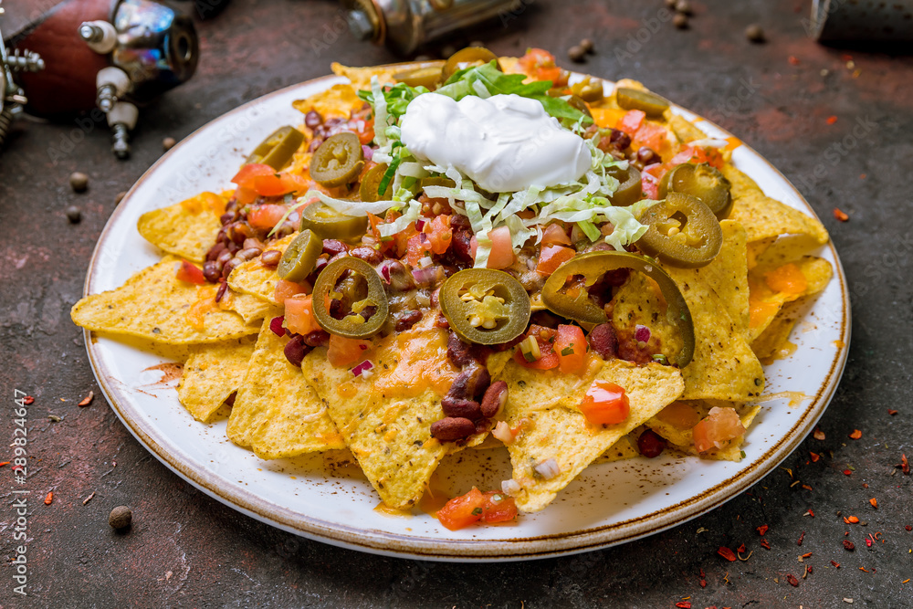 Mexican nachos chips with sauces on dark concrete rustic table Mexican nachos chips with sauces on dark concrete rustic table