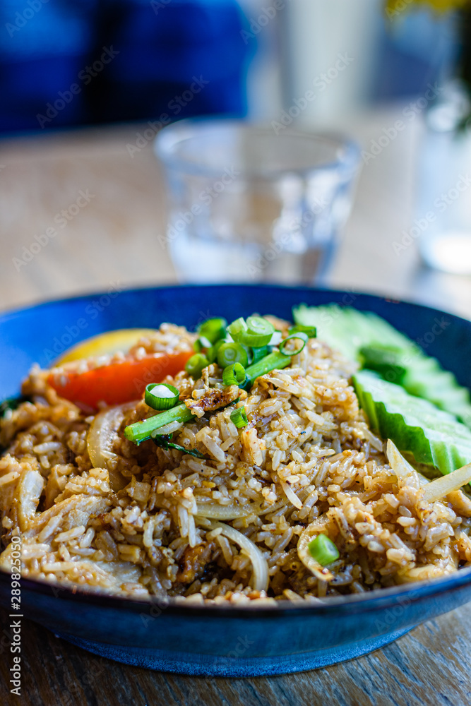 Thai chicken fried rice in a blue bowl on a restaurant table, close up. Thai chicken fried rice in a blue bowl on a restaurant table, close up.
