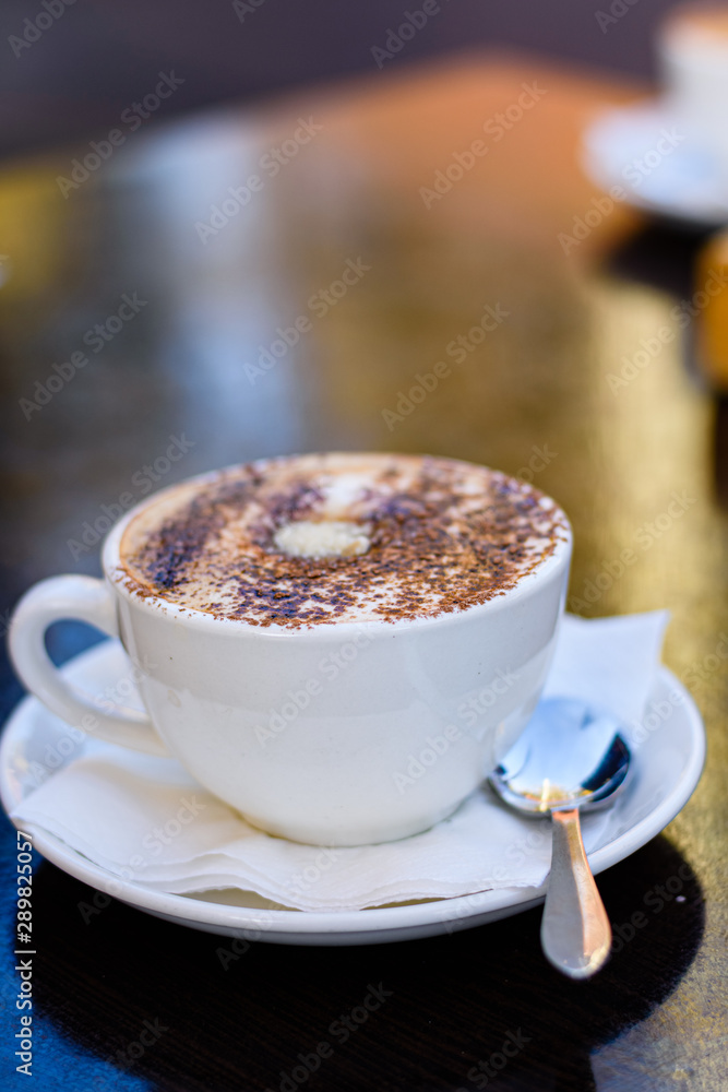 A cup of cappuccino coffee on a table, close up. A cup of cappuccino coffee on a table, close up.