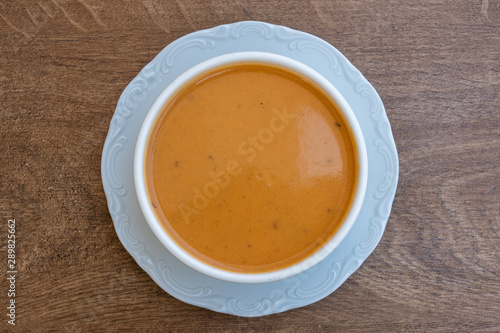 Vegetable cream soup with tomato, potato, squash in a white bowl, closeup