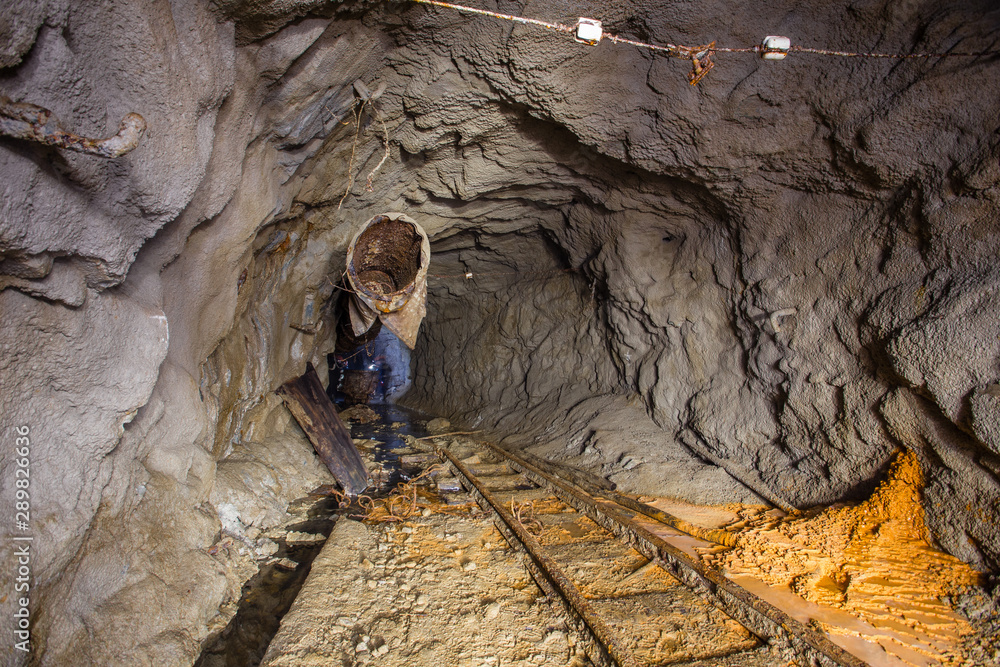 Gold ore mine shaft tunnel underground with rails