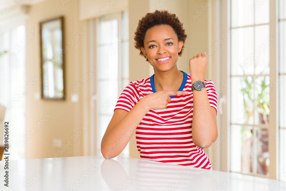 Young beautiful african american woman at home In hurry pointing to watch time, impatience, upset and angry for deadline delay Young beautiful african american woman at home In hurry pointing to watch time, impatience, upset and angry for deadline delay