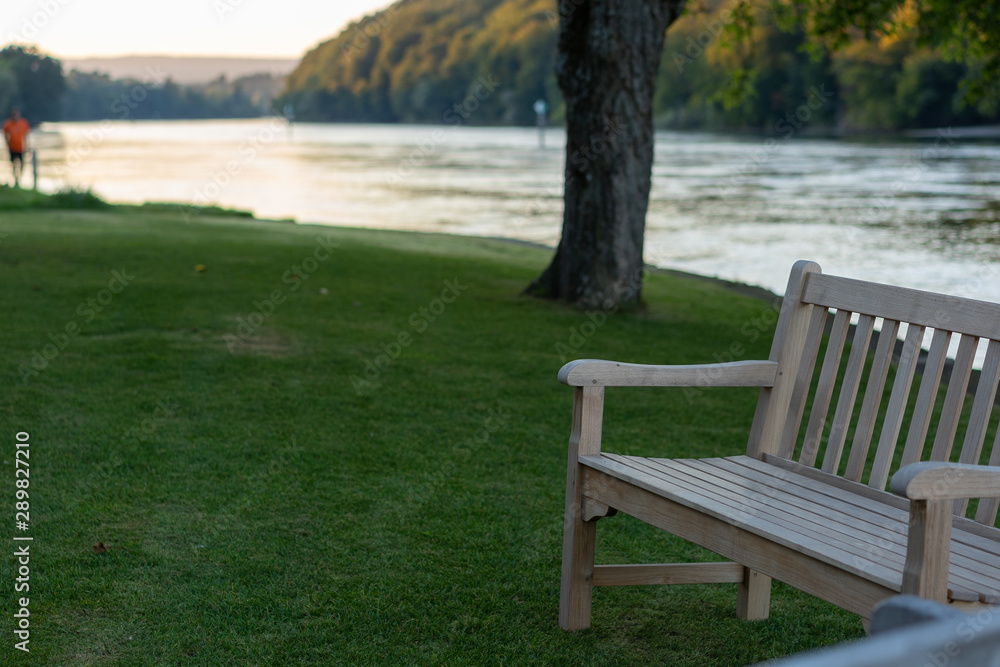 Two wooden benches in foreground with tree on the river bank at sunset in autumn. Two wooden benches in foreground with tree on the river bank at sunset in autumn.