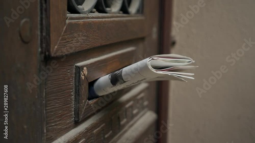 Postman puts a letter or newspaper or magazine in the mailbox at the door of a residential building or a person puts a brochure with advertising. Close-up