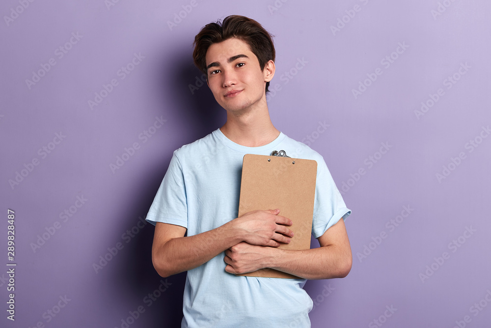 young handsome man holding folder, looking at the camera, preparing for a conference, education concept. isolated blue background. lifestyle young handsome man holding folder, looking at the camera, preparing for a conference, education concept. isolated blue background. lifestyle